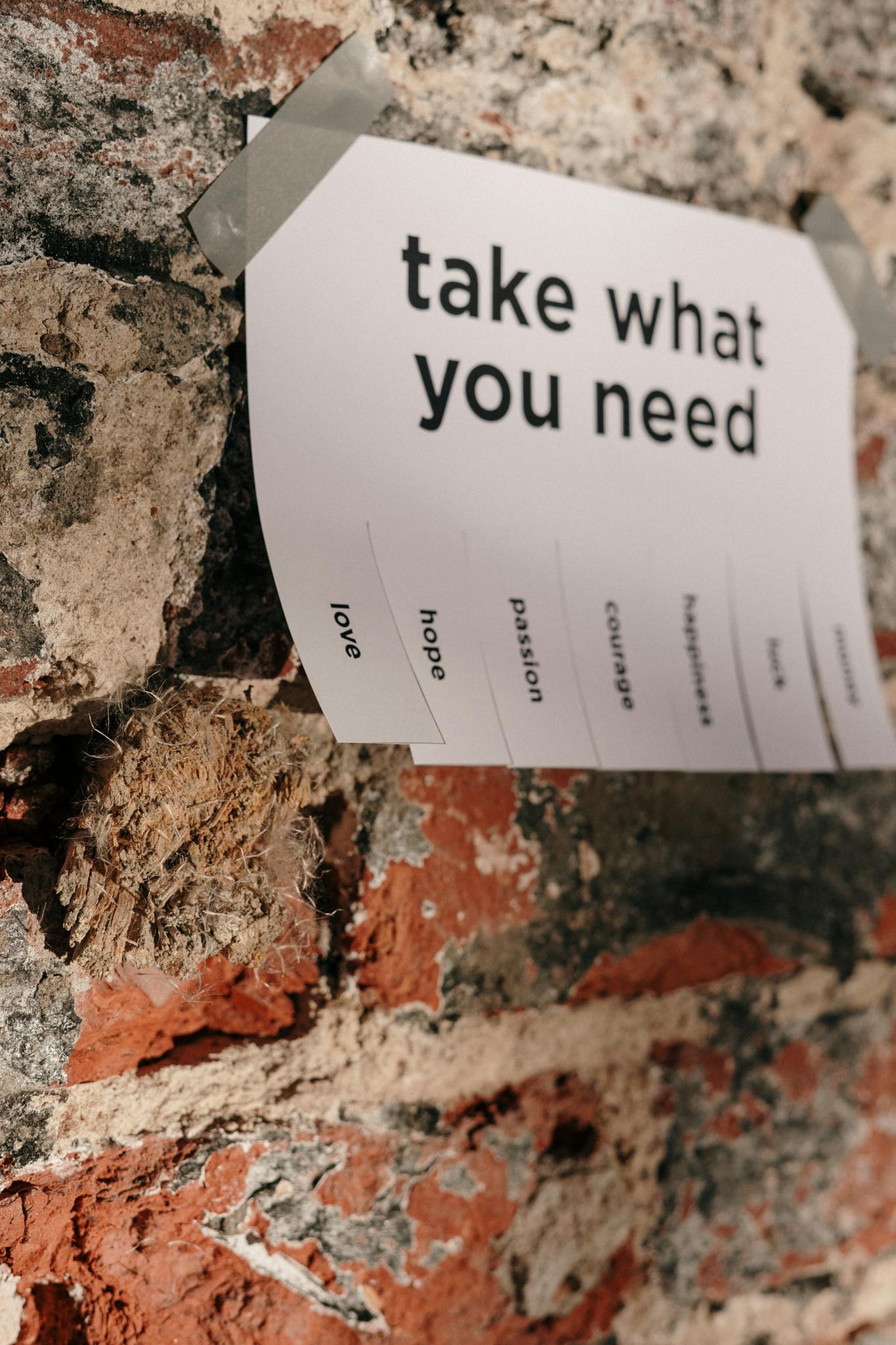 Close-up of a motivational note taped to a textured brick wall, urging positivity.